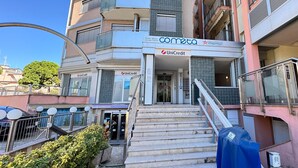 A multi-story building with a visible entrance, a staircase leading to the ground floor, and signage for 'commeta' and 'UniCredit'. - Il Giardino Delle Farfalle by Ca-sa Check (Chioggia)