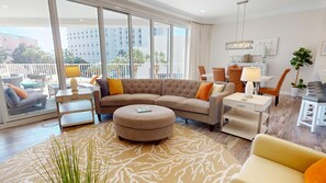 A modern living room with a sectional sofa, ottoman, and dining area.
