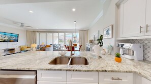A modern kitchen with a marble countertop, double sink, and white cabinetry.