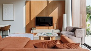 A modern living room with a large flat-screen TV, wooden paneling, a round coffee table, and a comfortable seating area. - SOLAIR Pererenan Loft #9 - 1 bdr - with pool and rooftop barbeque (Badung)