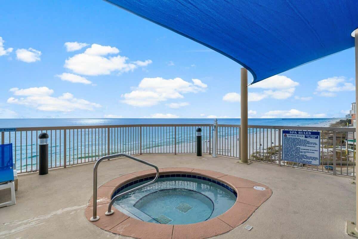 A hot tub on a balcony with a view of the beach and ocean.