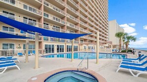 A hotel with multiple balconies, a swimming pool, and sun loungers.