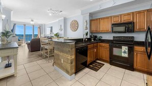 A modern kitchen with wooden cabinets, a built-in oven, and a large island with a dishwasher.