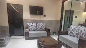 A modern living room with a sofa set, a coffee table, and a flat-screen TV mounted on the wall. - Hotel Lemon Park (Visakhapatnam)