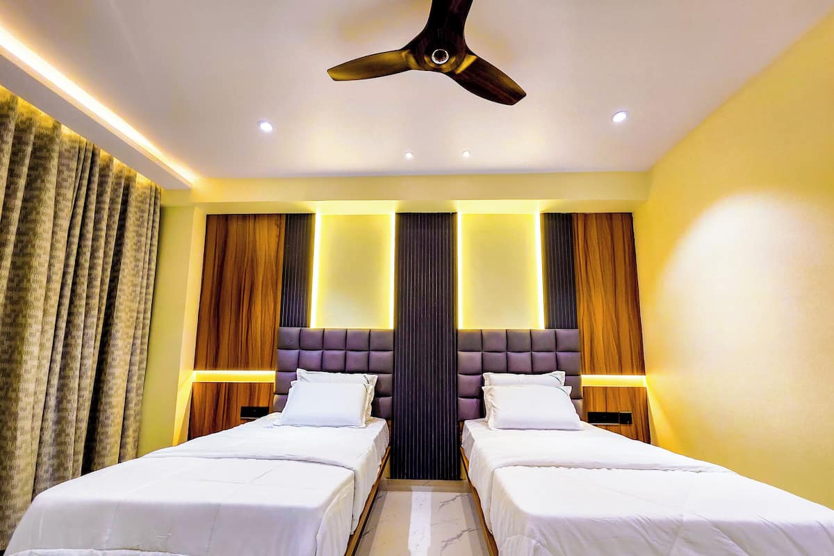 Ein Hotelzimmer mit zwei Betten, einem Deckenventilator und modernen Leuchten.