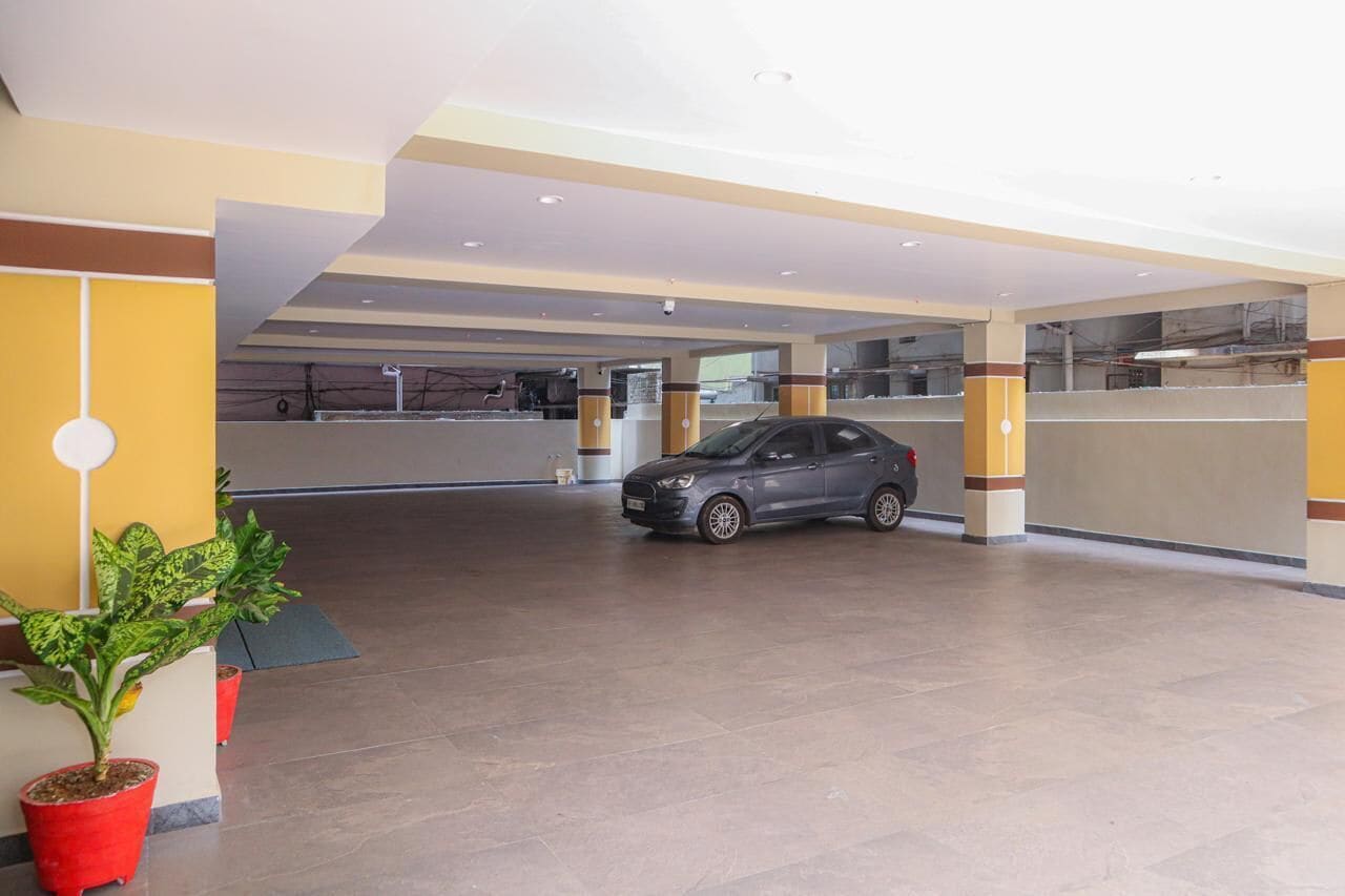 Estacionamento interno amplo, com um carro estacionado, plantas em vasos e um design de teto moderno.