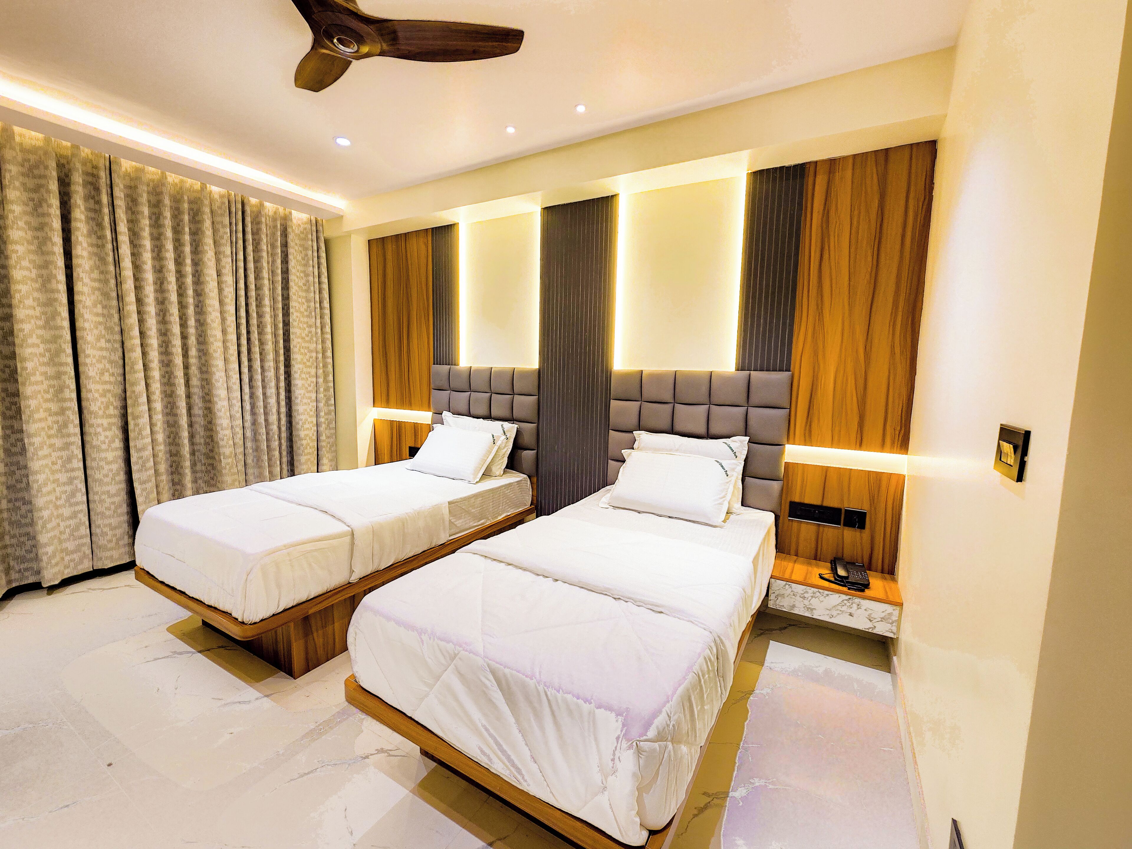 Habitación de hotel con dos camas, ventilador de techo y diseño moderno.