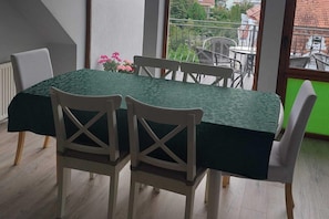 A dining table with a green tablecloth, white chairs, and a flower arrangement.