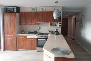 Une cuisine moderne avec des meubles en bois, une cuisinière à gaz, un four et une machine à café.