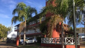 A multi-story building with balconies, parked cars, and palm trees. - Mirador del Dayman  (Termas del Dayman)