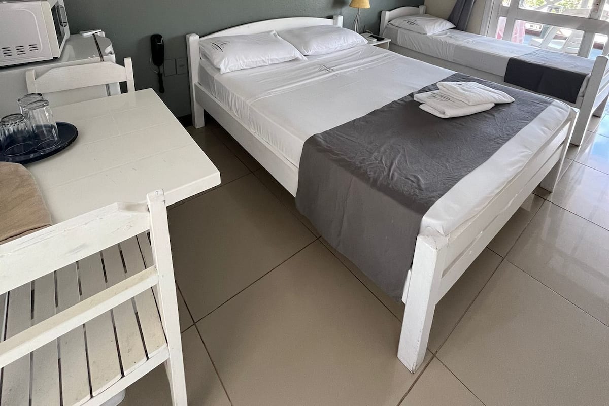 A bedroom with a bed, a desk, a chair, a lamp, and a window.