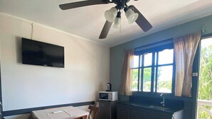 A compact kitchen with a dining area, a ceiling fan, a TV mounted on the wall, and a window with curtains. - Mirador del Dayman  (Termas del Dayman)