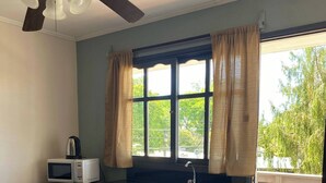 A compact kitchen with a microwave, a sink, and a ceiling fan. - Mirador del Dayman  (Termas del Dayman)