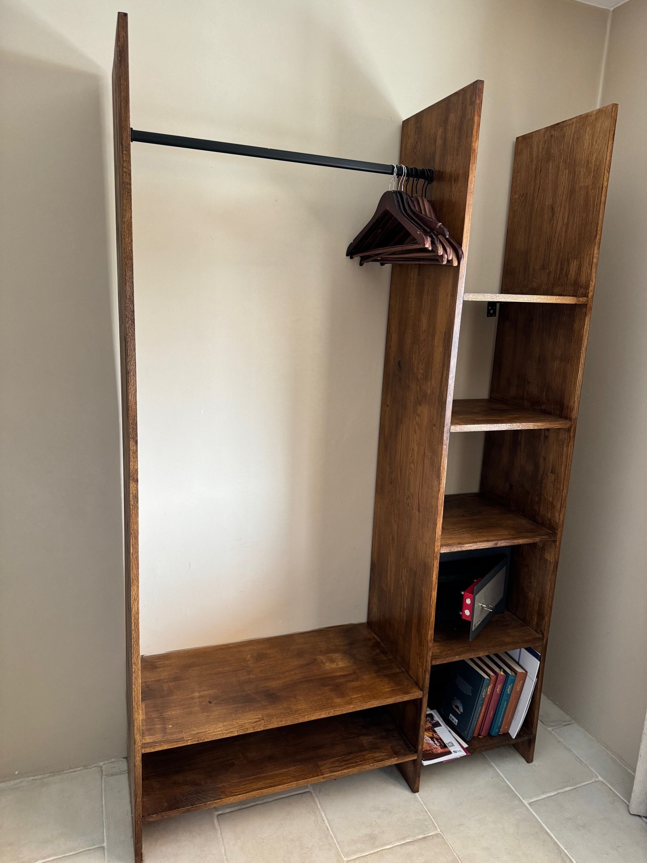 A wooden wardrobe with a hanging rod and open shelves.