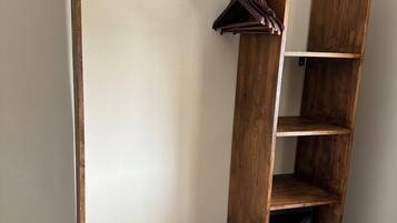 A wooden wardrobe with a hanging rod and open shelves.