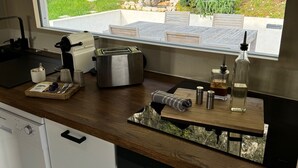 A modern kitchen with a built-in oven, a dishwasher, and a window overlooking a garden. - Waterfront house Les Roches  (Rochefort-sur-Nenon)