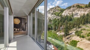 A modern interior with large windows overlooking a mountainous landscape. - Architectural Gem by InvitedHome | Ski-In, Sauna, Patio, Firepit, Unique (Alta)