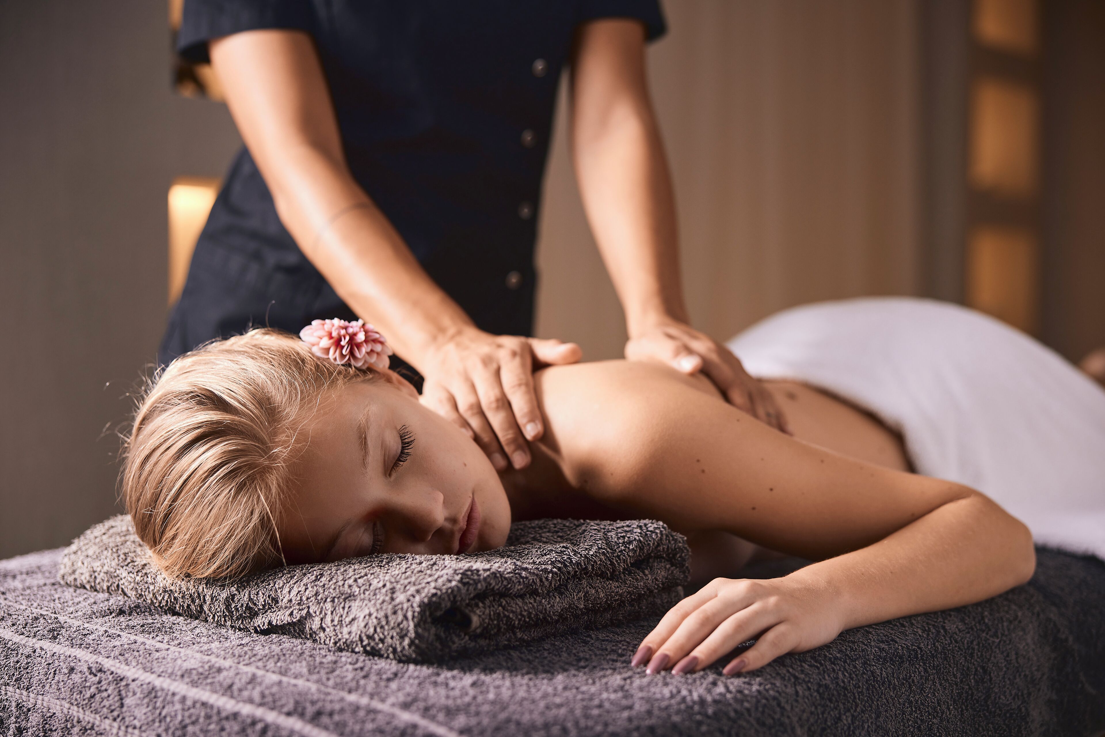 Iemand ontvangt een massage op een massagetafel, met een handdoek en een deken.