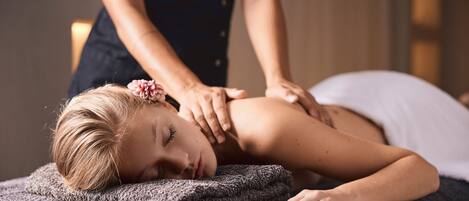 Iemand ontvangt een massage op een massagetafel, met een handdoek en een deken.