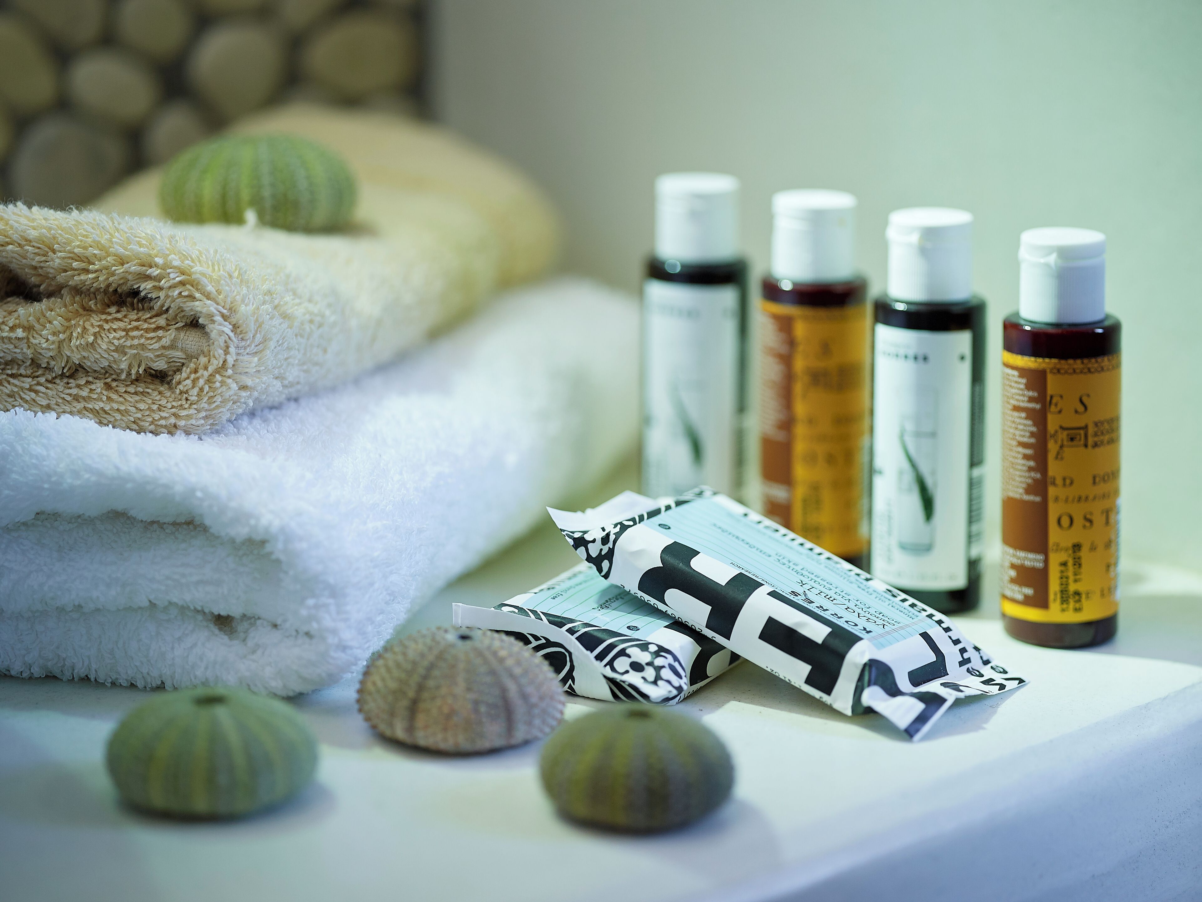 A neatly arranged set of towels, bath products, and decorative shells on a surface.