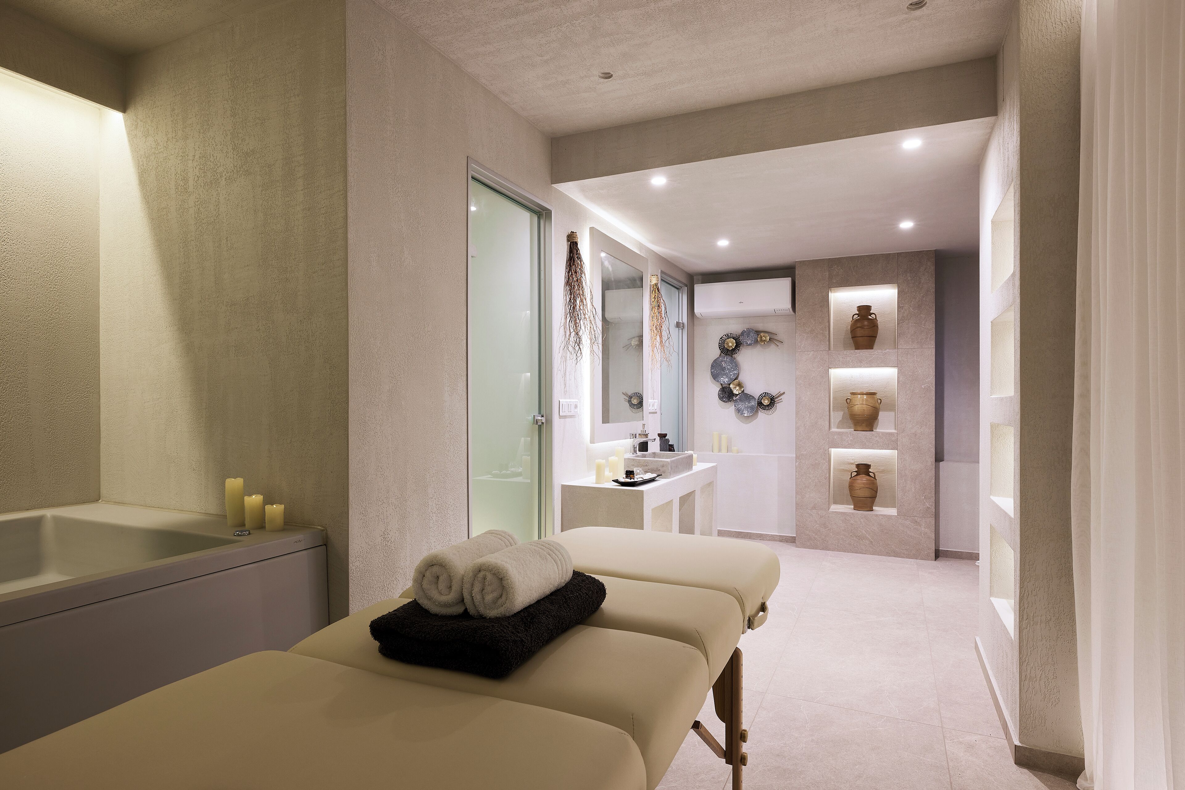 Ein moderner Wellnessraum mit Massagetisch, Badewanne und Schminktisch mit Spiegel und Waschbecken.