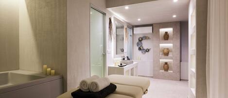 Ein moderner Wellnessraum mit Massagetisch, Badewanne und Schminktisch mit Spiegel und Waschbecken.