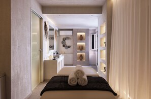 A modern hotel room with a bed, a bathroom, and a small sitting area. - Garifalakis Comfort Rooms (Milos)