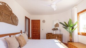 A bedroom with a bed, wooden dresser, and a large plant. - Villa VENTURA by Abahana Villas (Calpe)