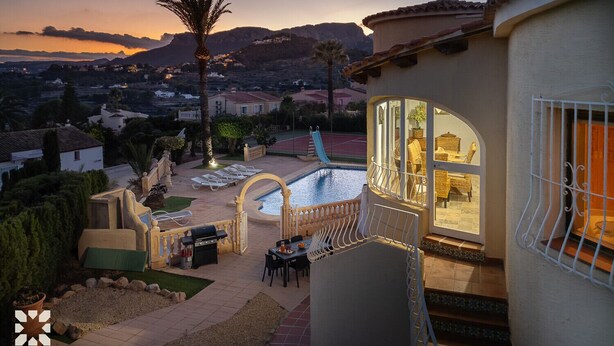 A pool area with a slide, outdoor seating, and a view of a residential neighborhood at sunset. - Villa VENTURA by Abahana Villas (Calpe)
