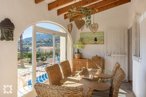 Relax in this serene room with a pool view, wicker furniture, and a wooden cabinet.