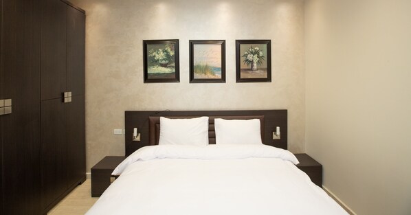 A hotel room with a large bed, two bedside tables, and three framed artworks on the wall. - Prime Select Lotus New Cairo (New Cairo)