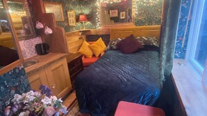 Ein gemütliches Schlafzimmer mit einem großen Bett, einer Holzkommode, einem Schminktisch mit Spiegel und einem Fenster mit Blick.
