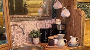 Eine Küche mit Holzausstattung, einem Spülbecken, einer Kaffeemaschine und hängenden Tassen.