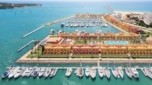 A marina with numerous boats docked, a large building complex with a pool, and a beach in the background. - Rorippa Apartment, Portimao, Algarve (Portimão)