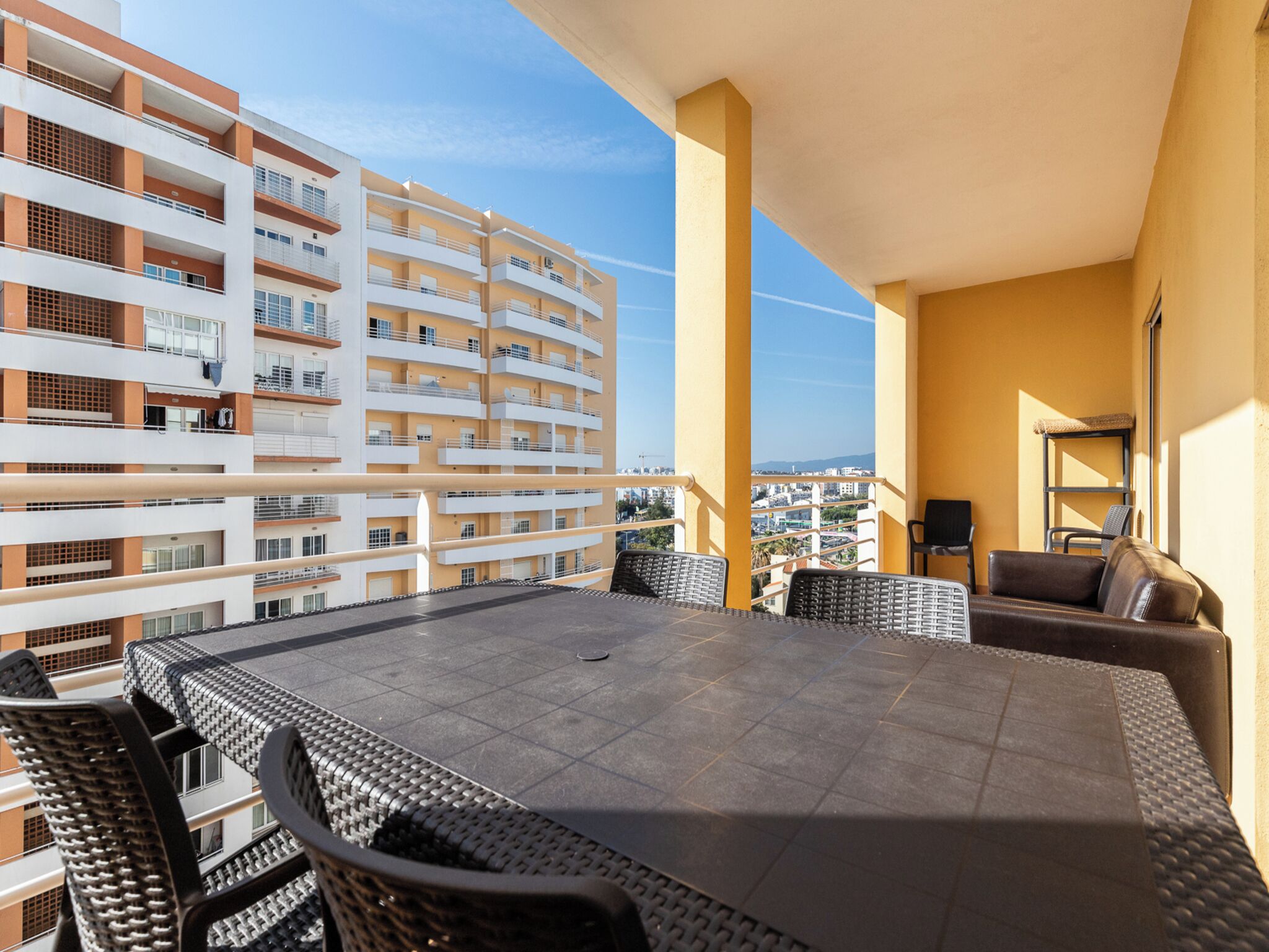 A balcony with a dining table, chairs, and a sofa.