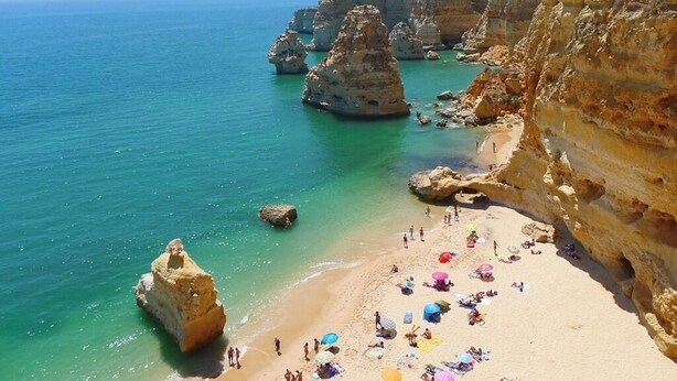 A beach with clear turquoise water, rocky formations, and people sunbathing. - Rorippa Apartment, Portimao, Algarve (Portimão)