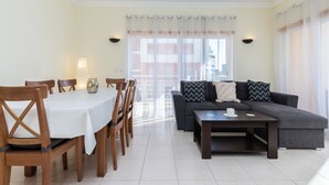 A modern living room with a dining area, featuring a sofa set, a coffee table, and a dining table with chairs. - Rorippa Apartment, Portimao, Algarve (Portimão)