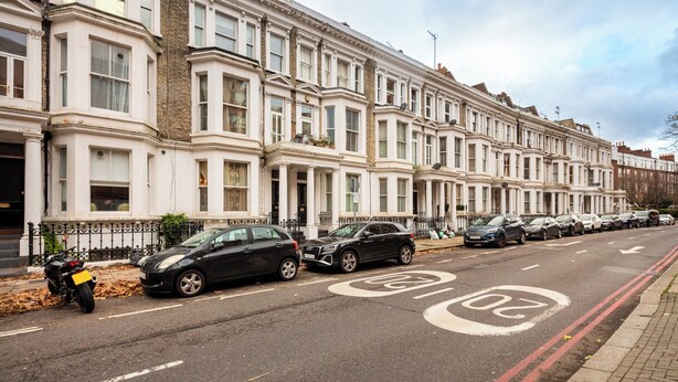 A row of white terraced houses with parked cars on the street.