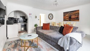 A modern living room with a sofa, coffee table, and a kitchen in the background.