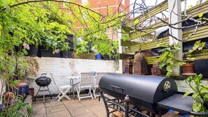 A backyard with a barbecue grill, outdoor furniture, and potted plants.