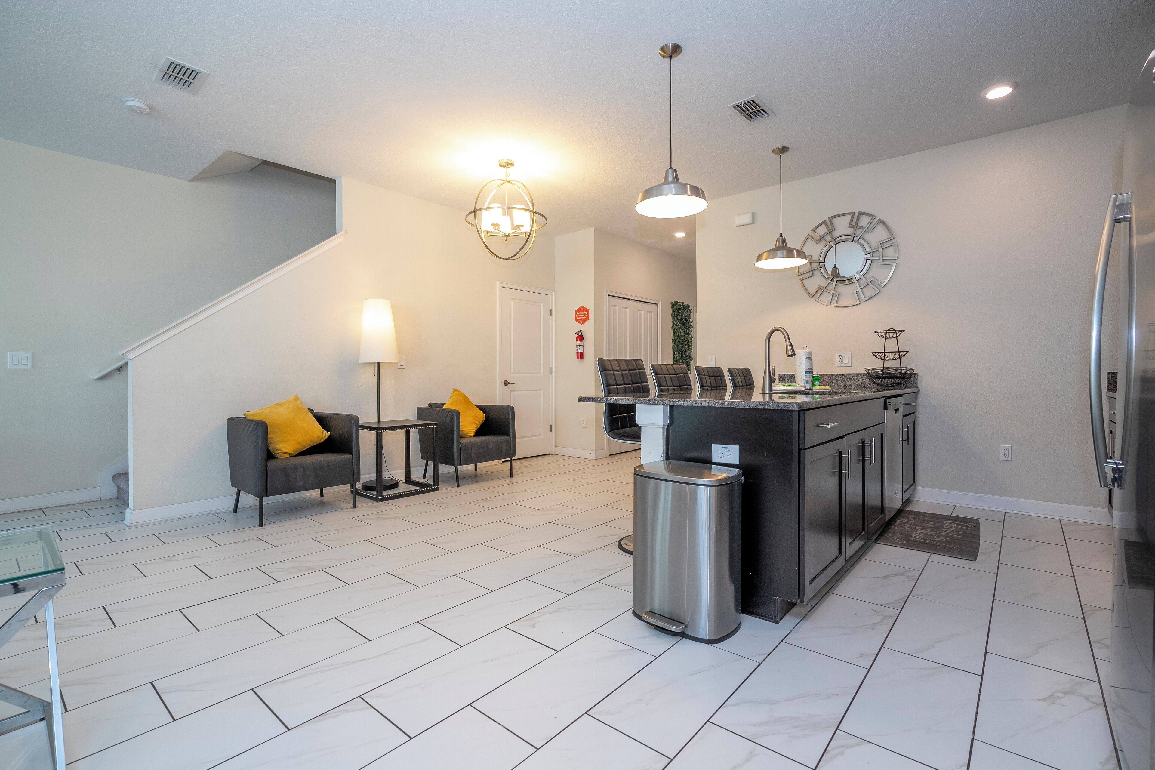 A modern kitchen with a central island, stainless steel appliances, and a dining area with two sofas and a table.