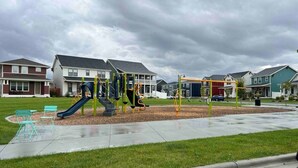 A playground with slides and swings, surrounded by houses and a grassy area. - Charming 2-bedroom townhome with WiFi, AC/Heat in delightful Billings (Billings)