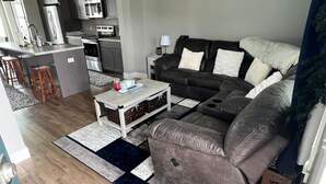 A modern living room with a leather sofa, a coffee table, and a kitchen area in the background. - Charming 2-bedroom townhome with WiFi, AC/Heat in delightful Billings (Billings)
