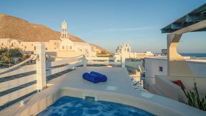 A rooftop pool with a view of white buildings and a hill in the background.