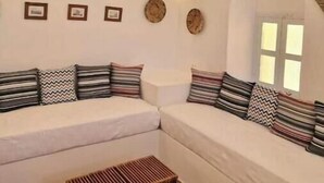 A cozy living room with a white sofa set, a wooden coffee table, and decorative wall art.