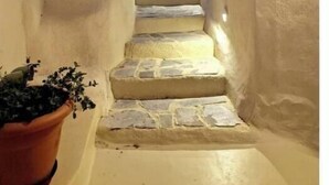 A narrow, stone-floored stairway leading up to a building with white walls.