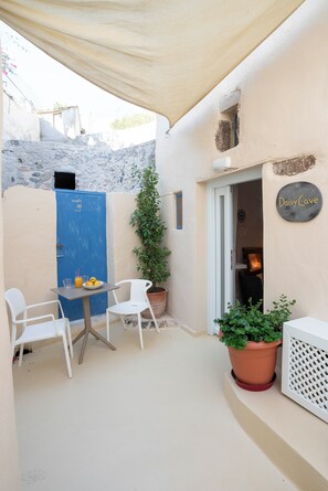 A small outdoor seating area with a table, two chairs, and a potted plant.