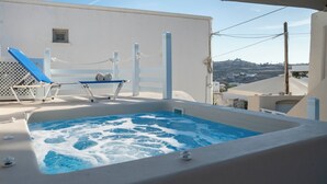 Un área de piscina en la azotea con un jacuzzi, sillones de descanso y vistas del paisaje circundante.