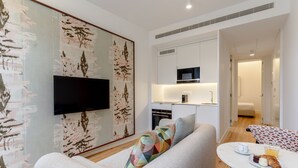 A modern living room with a sofa, a flat-screen TV mounted on the wall, and a dining area with a table set for breakfast. - Feel Porto Cl Rigos Charm Flat 2 3 (Porto)