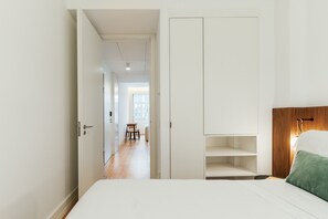 A bedroom with a bed, a wooden headboard, a green pillow, and a white wardrobe. - Feel Porto Cl Rigos Charm Flat 2 3 (Porto)